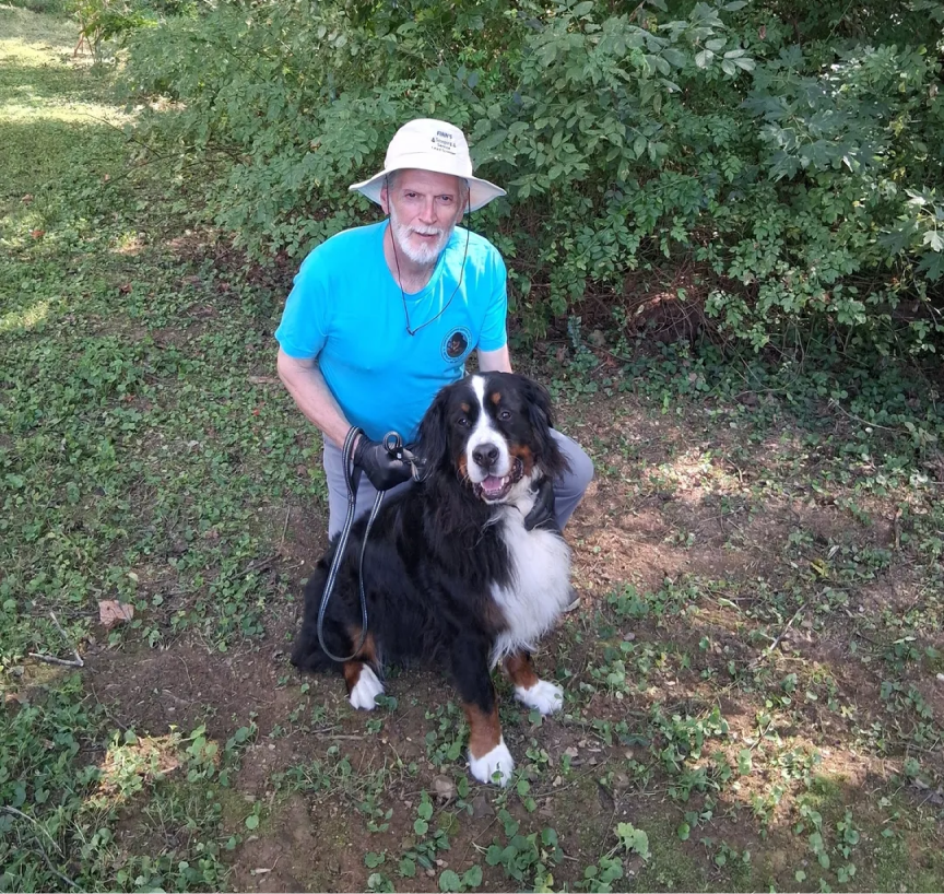 Man with dog in a forest clearing.