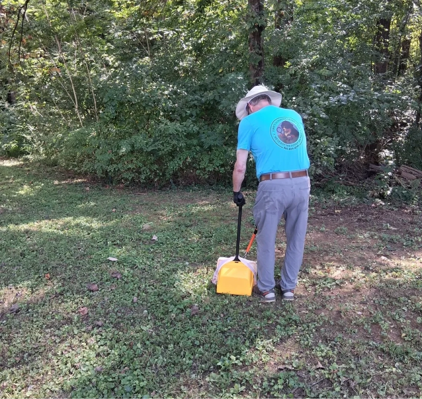 Man cleaning up leaves in wooded area.